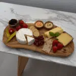 Servierbrett aus Olivenholz mit Antipasti auf Marmortisch